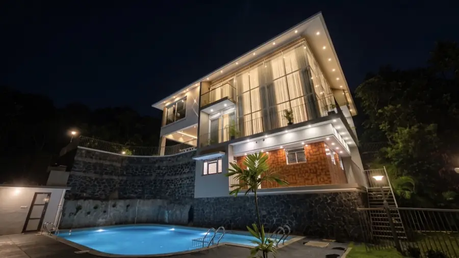 The mansion lit at night above the pool
